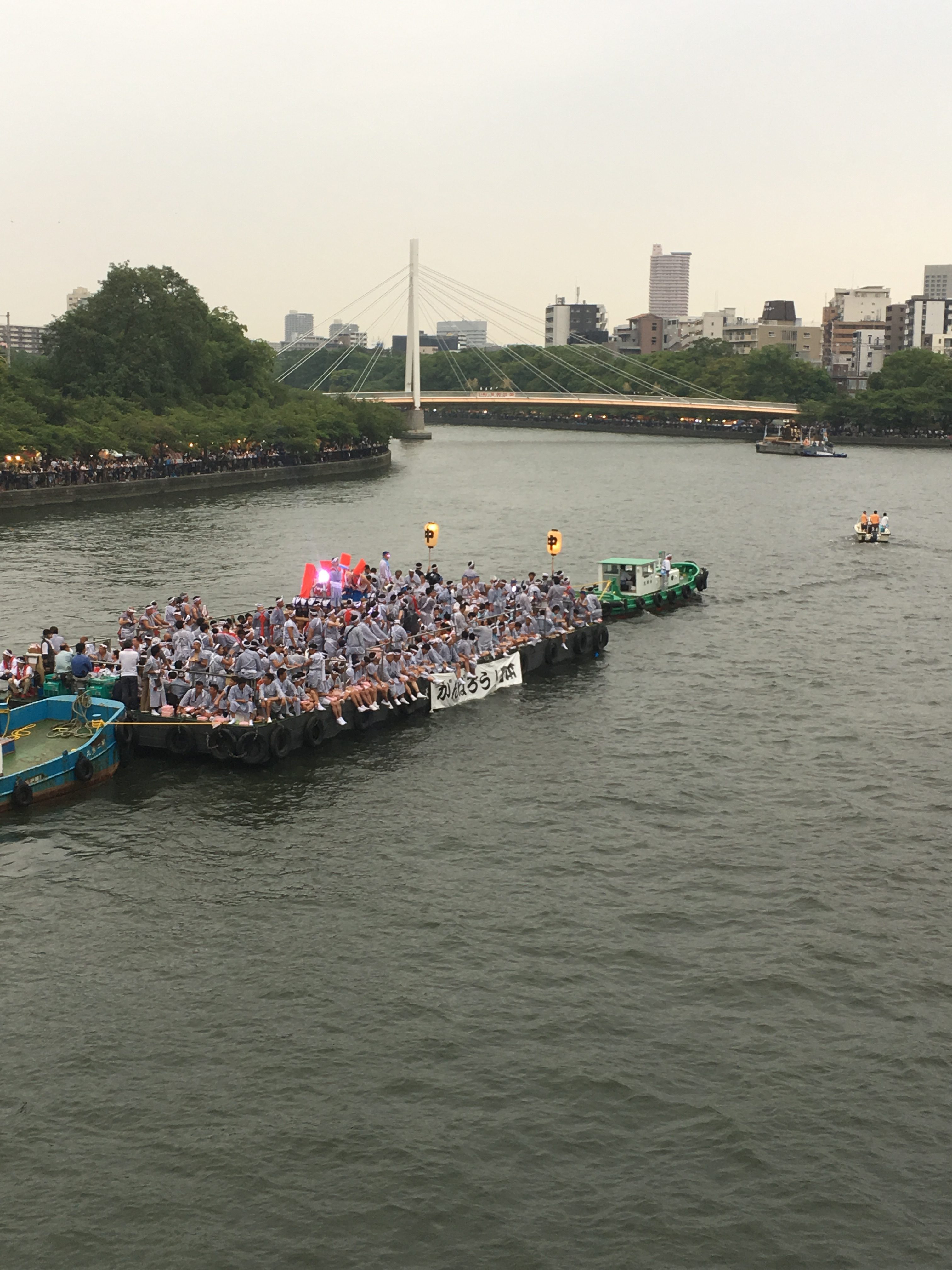 small tug boat carrying people down the river during tenjin matsuri