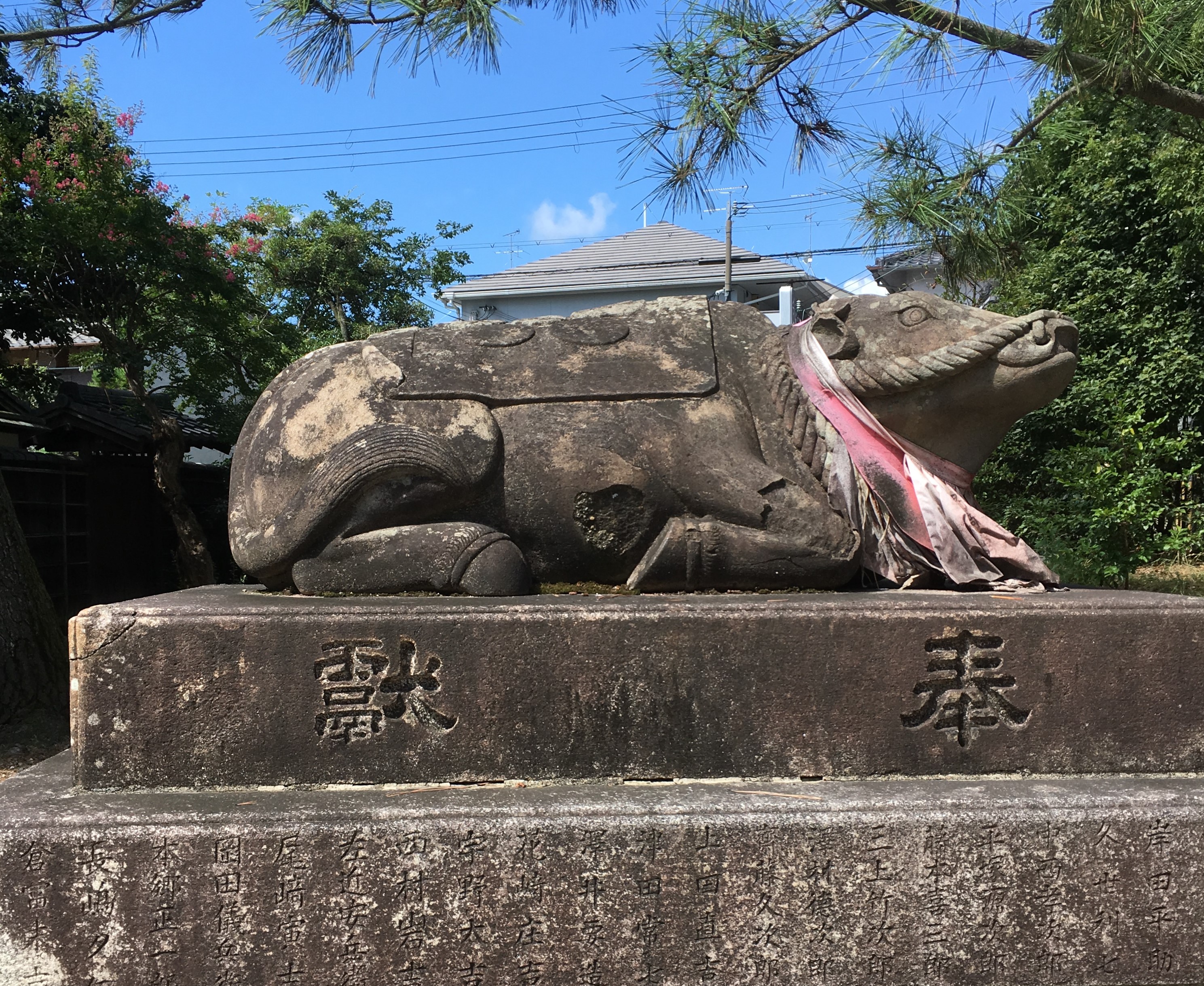 statue of stone cow lying down with a red bib