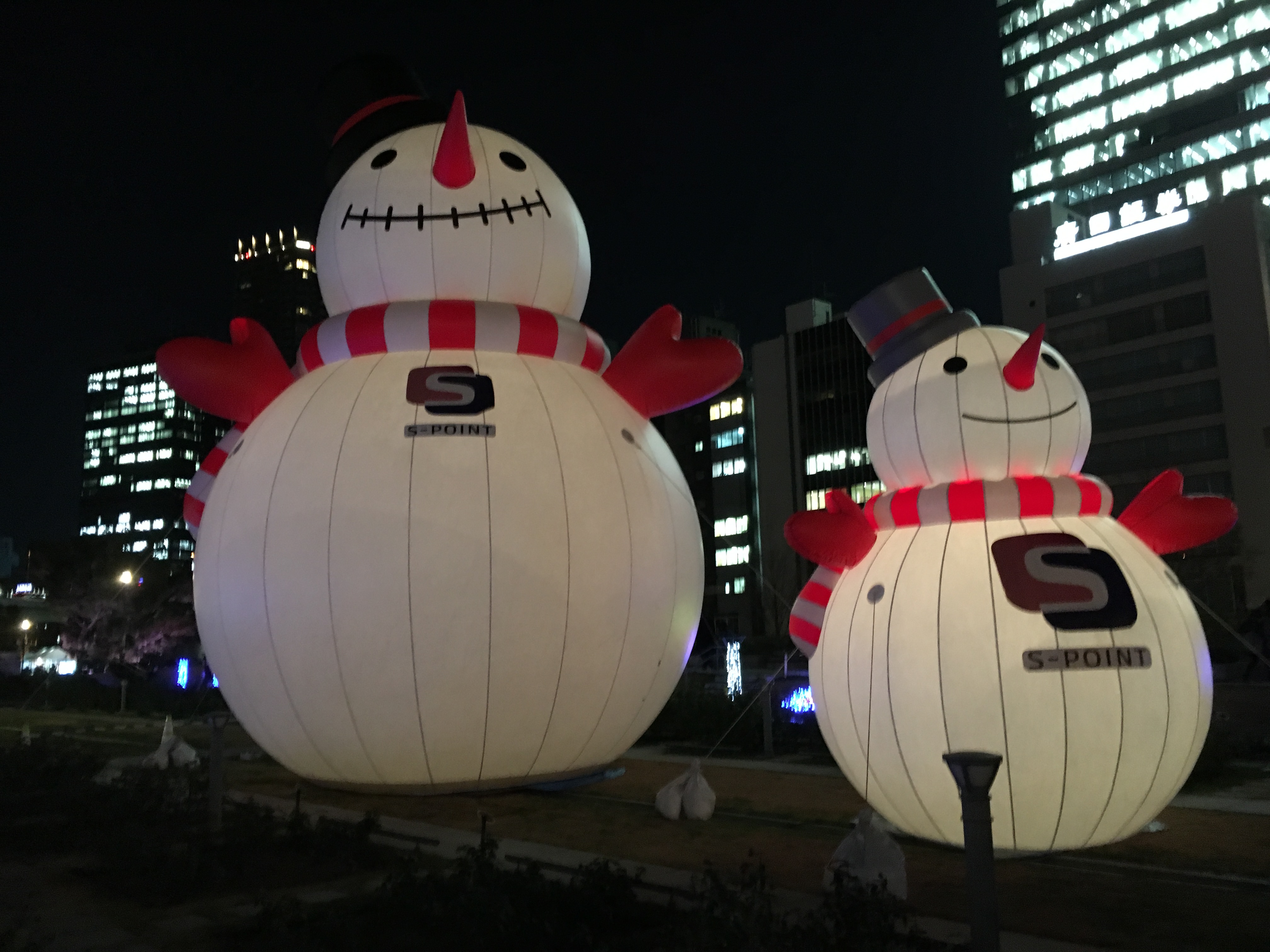 two inflatable snow man standing over a crowd