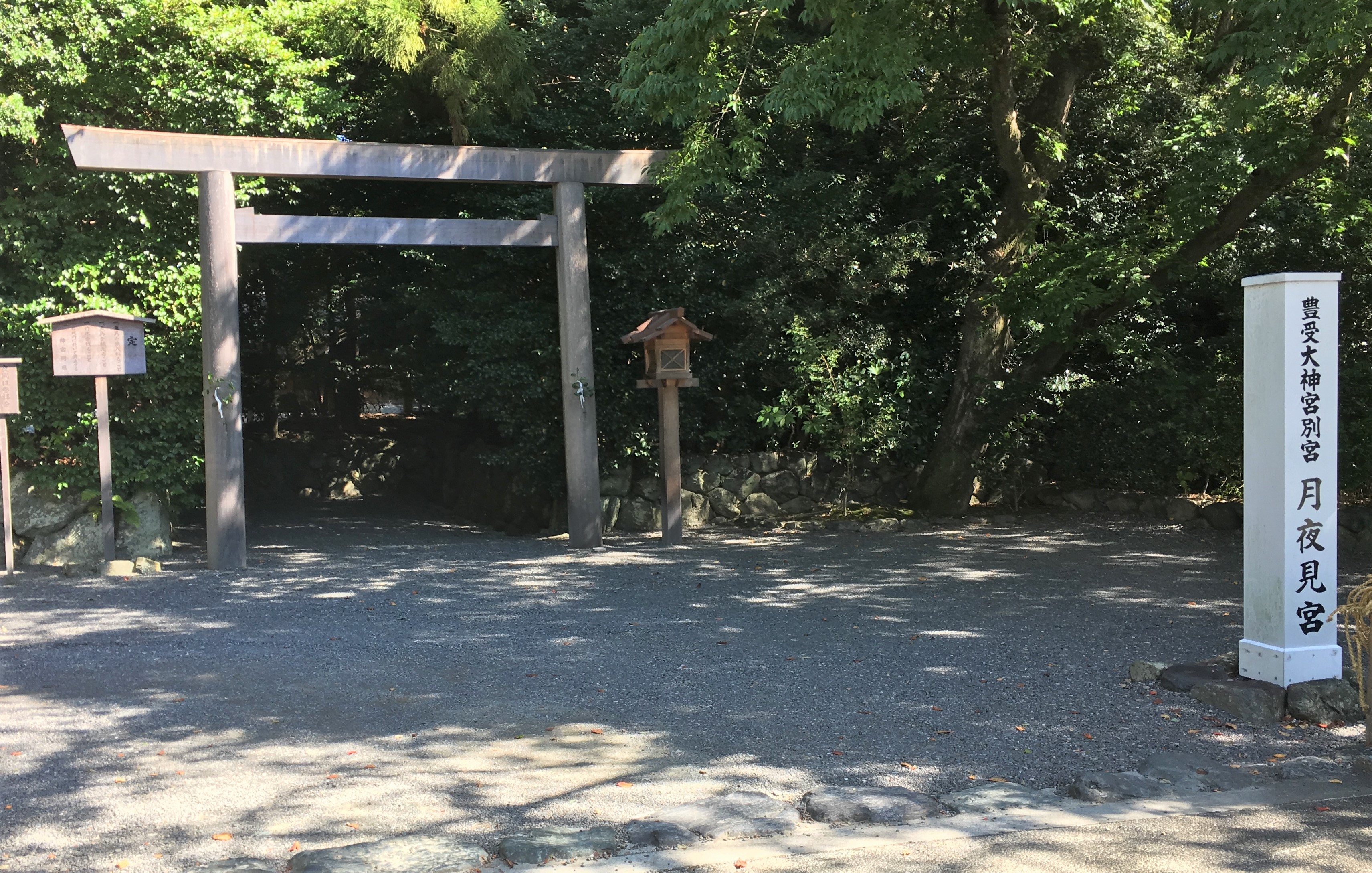 entrance of tsukiyomi no miya guarded by wood torii standing on a gravel lawn