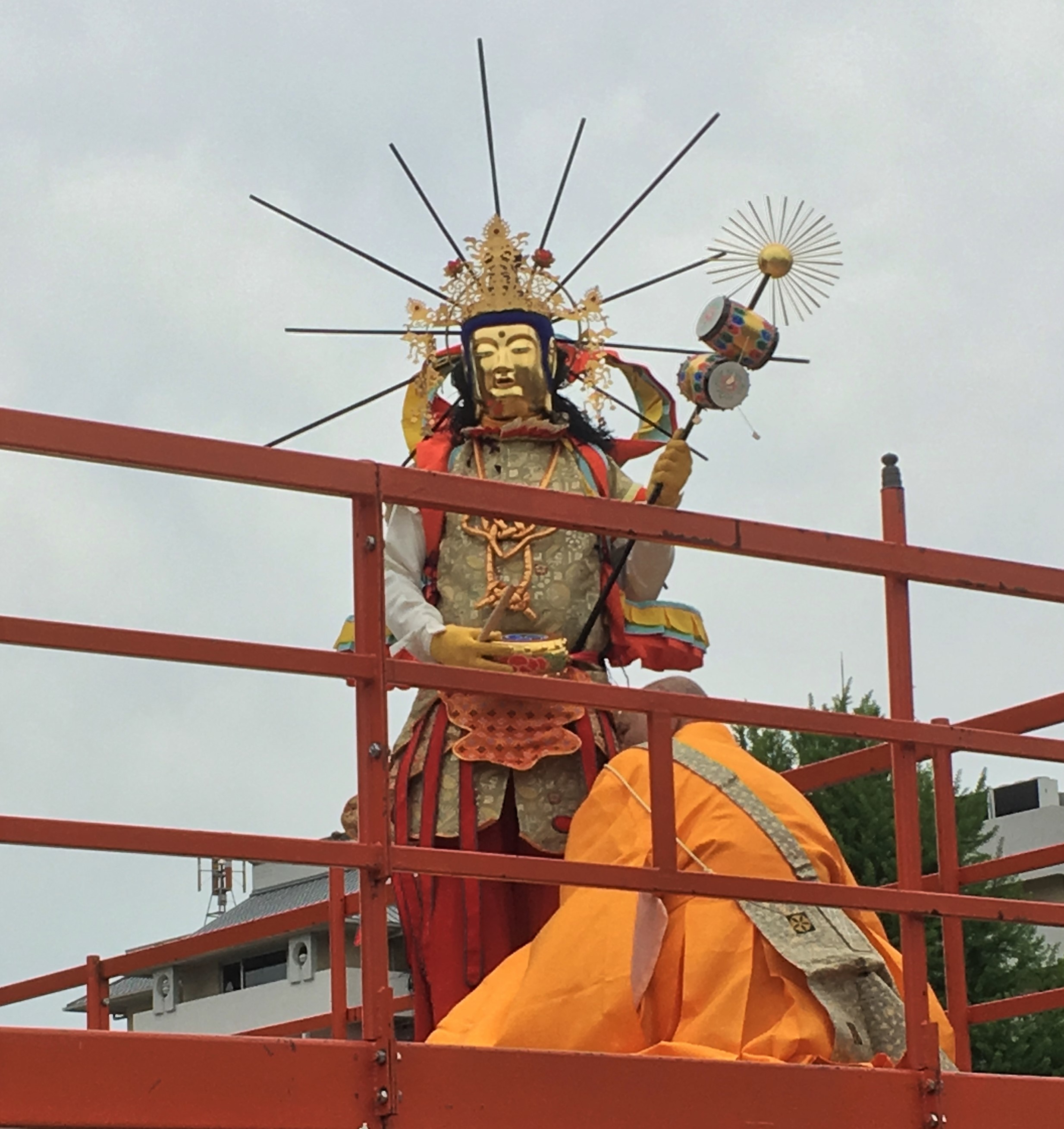 A pbuddhist priest dressed in orange kneeling before a man dressed as a bosatsu