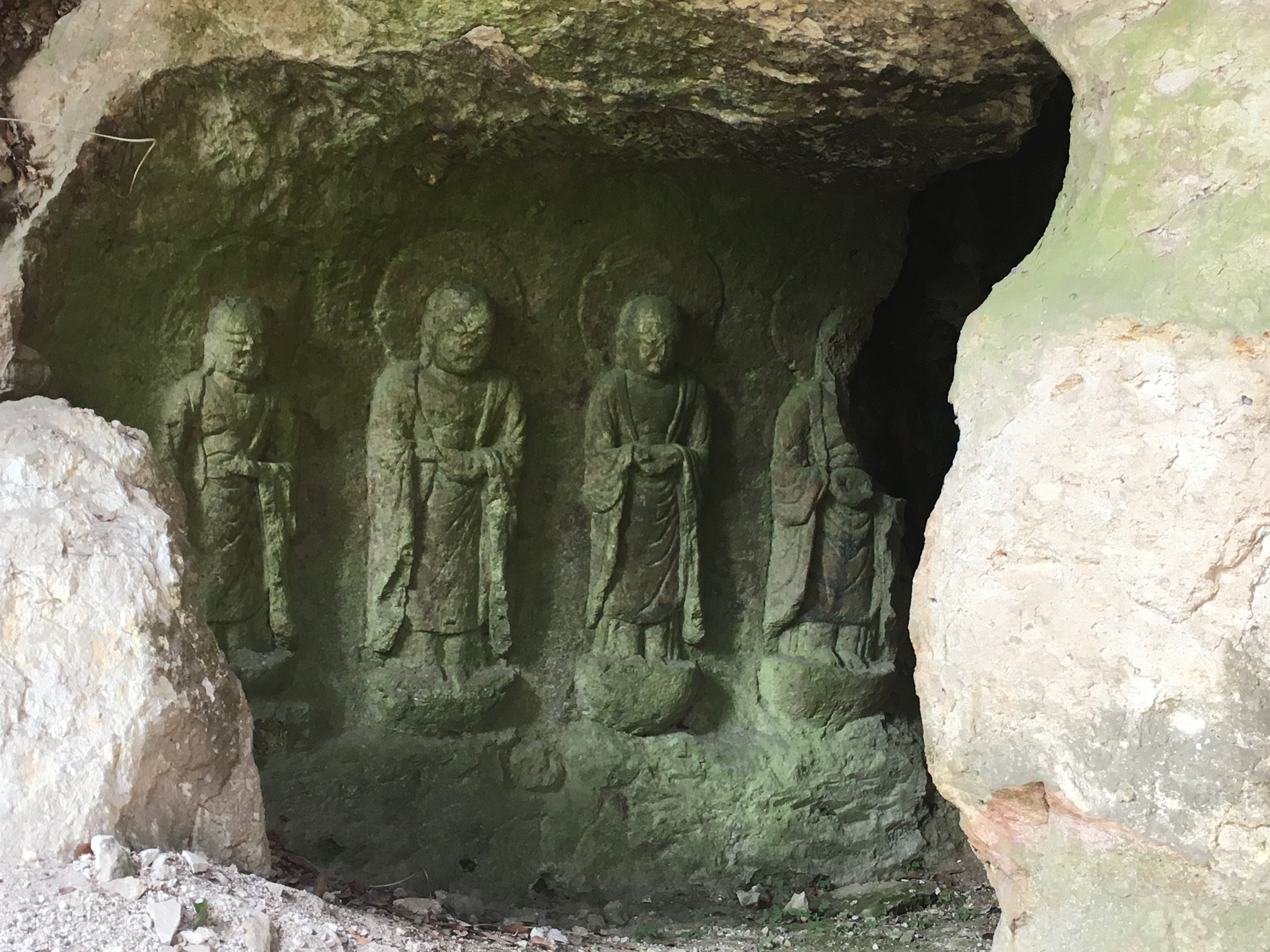 four buddha carved into a rock face, most of the fourth missing