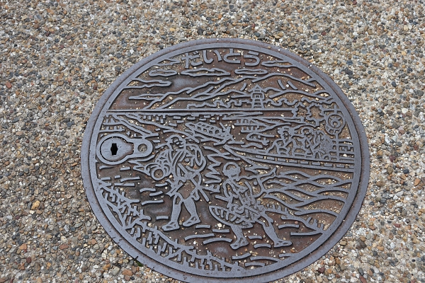 manhole depicting people going to Nozaki