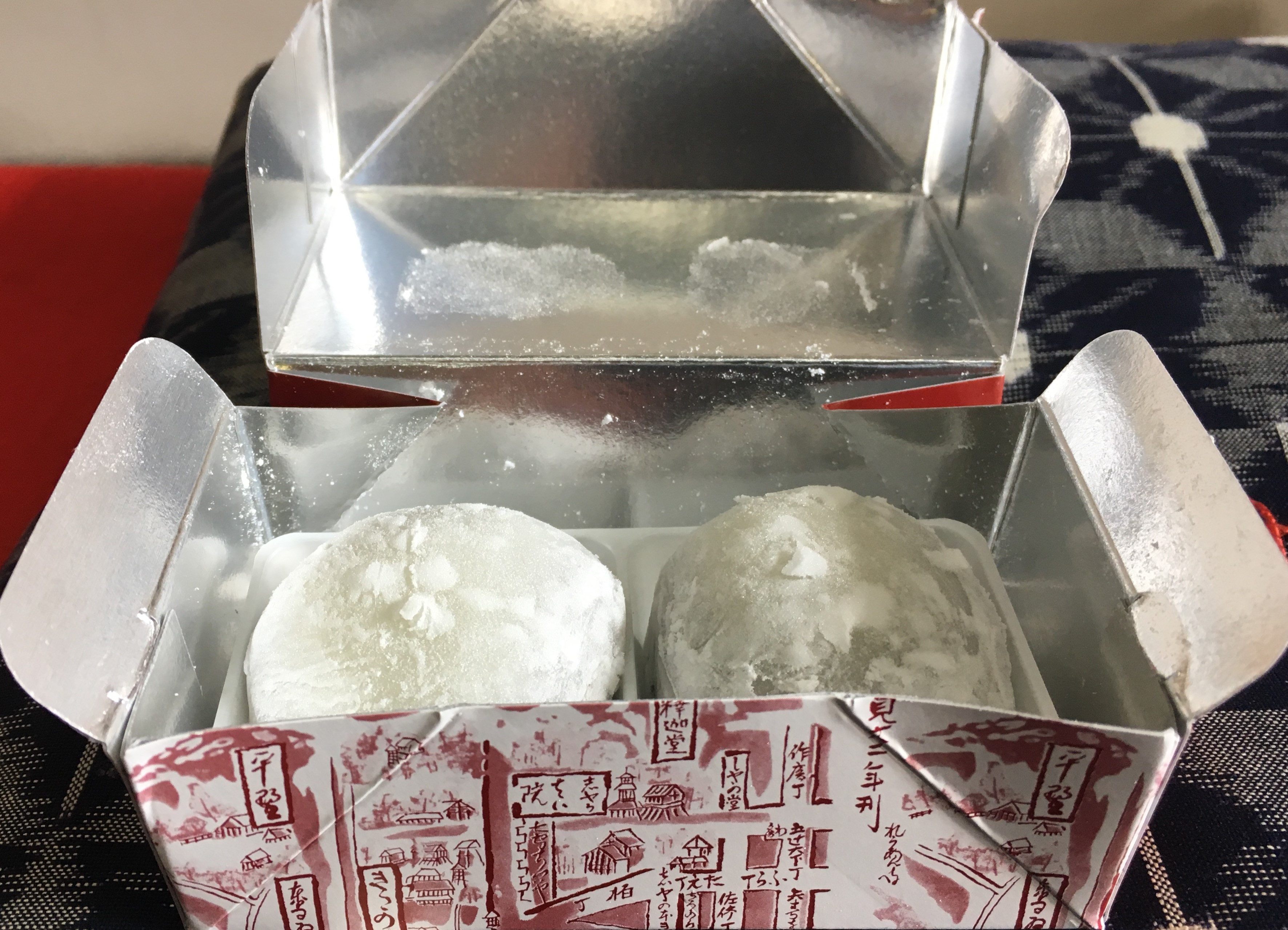 two white pillowy looking balls of mochi in a red and white box