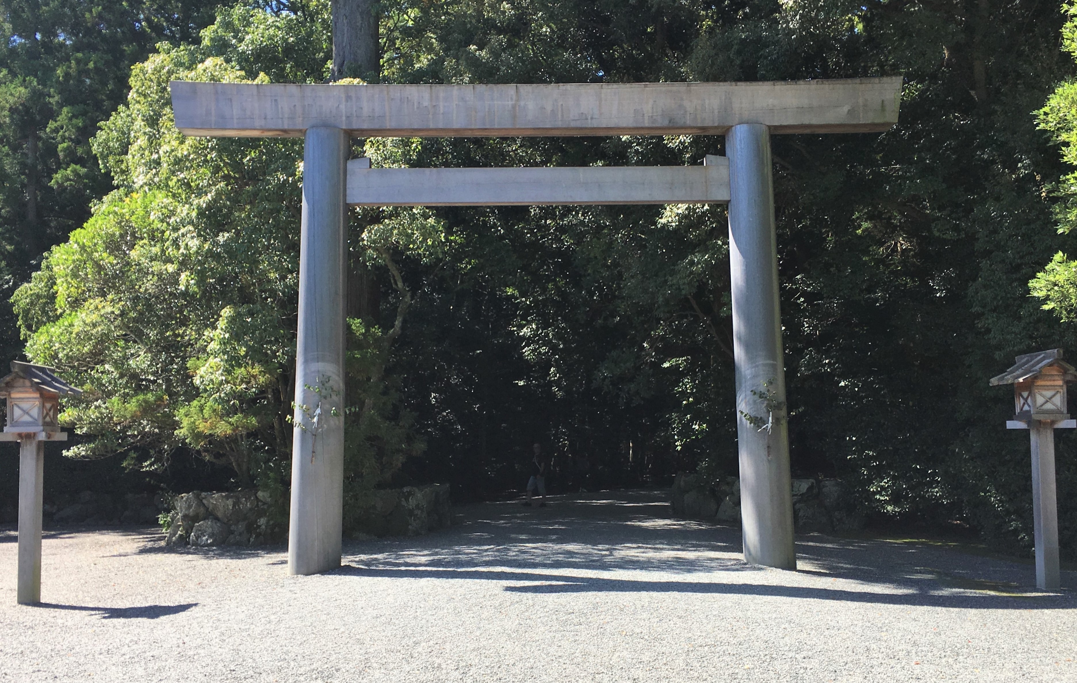 wooden torii of geku leading down a dark tree lined gravel path