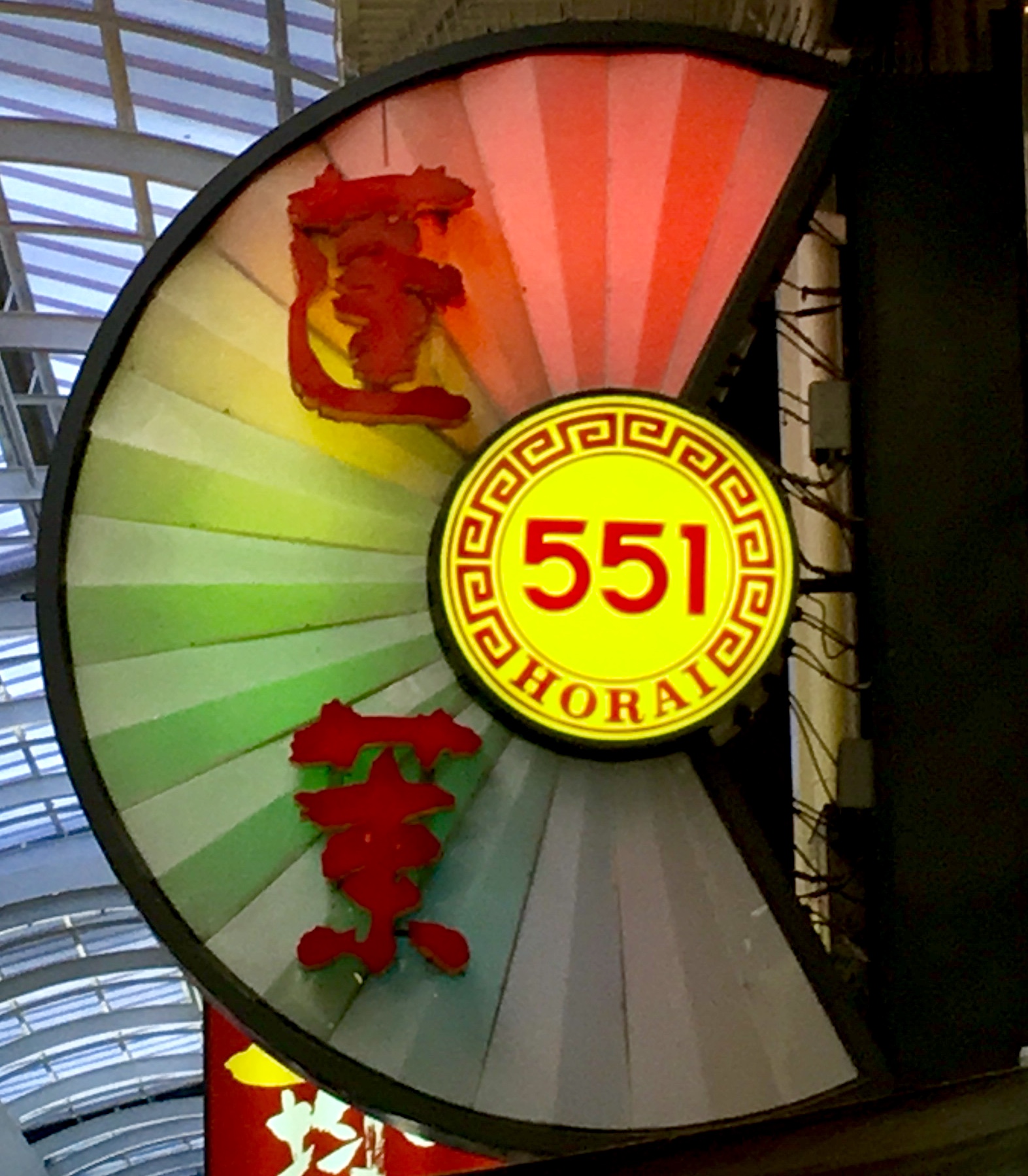 Half circle shaped rainbow colored neon sign for a restaurant and the numbers 551