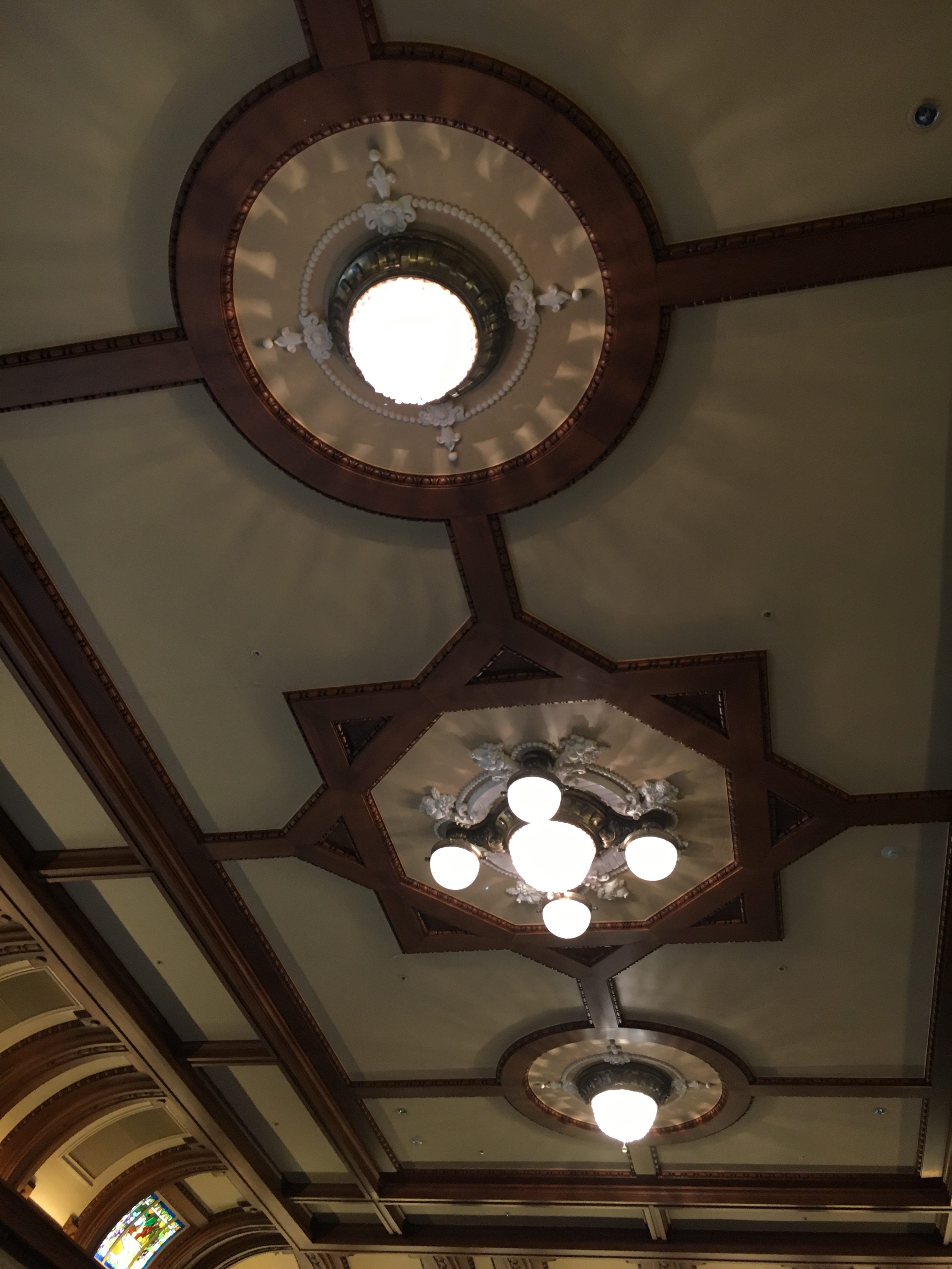 three crystal chandeliers surrounded by crown molding and wood details