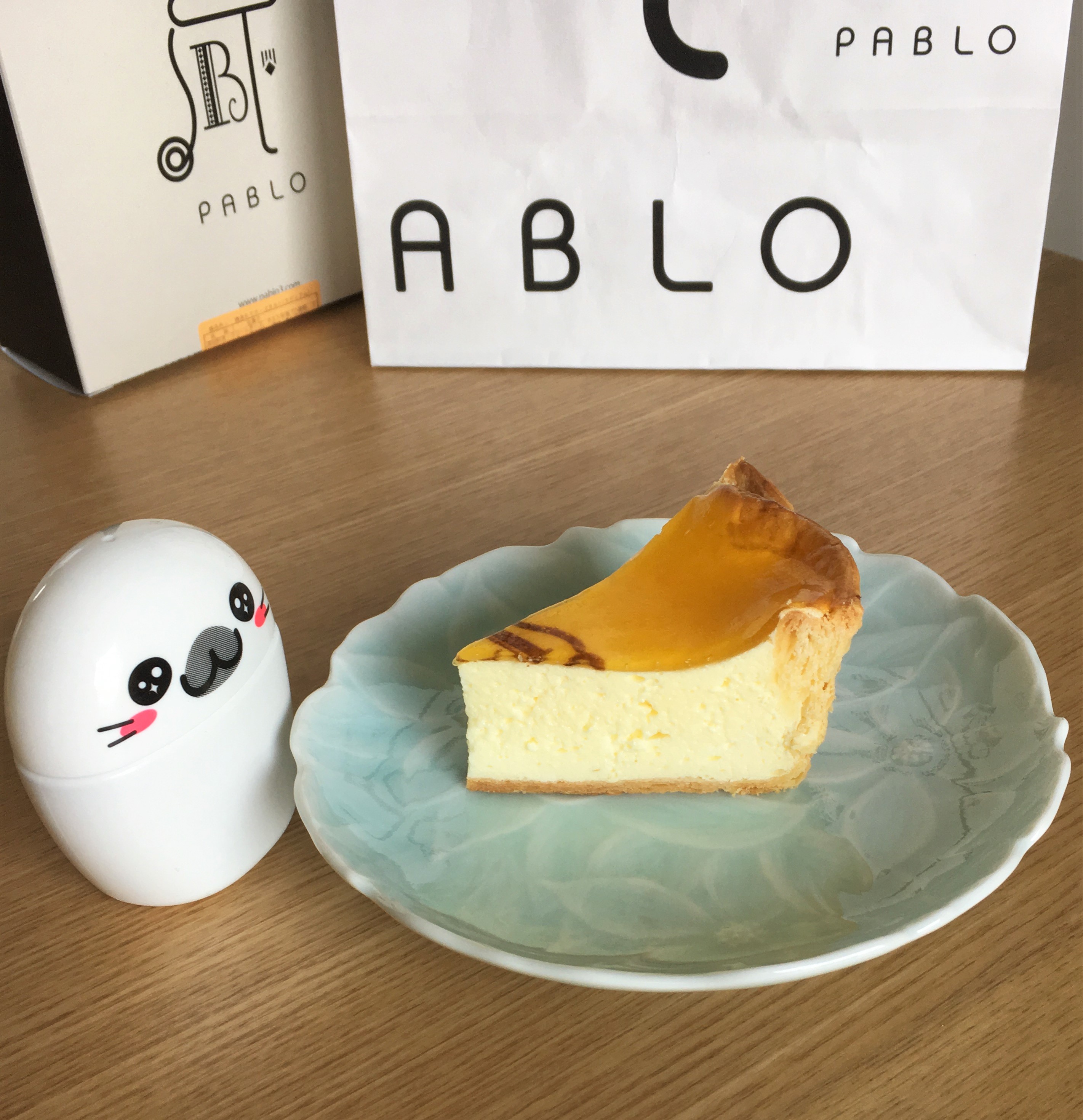 slice of Pablo cheesecake on a blue plate and pablo bags in background
