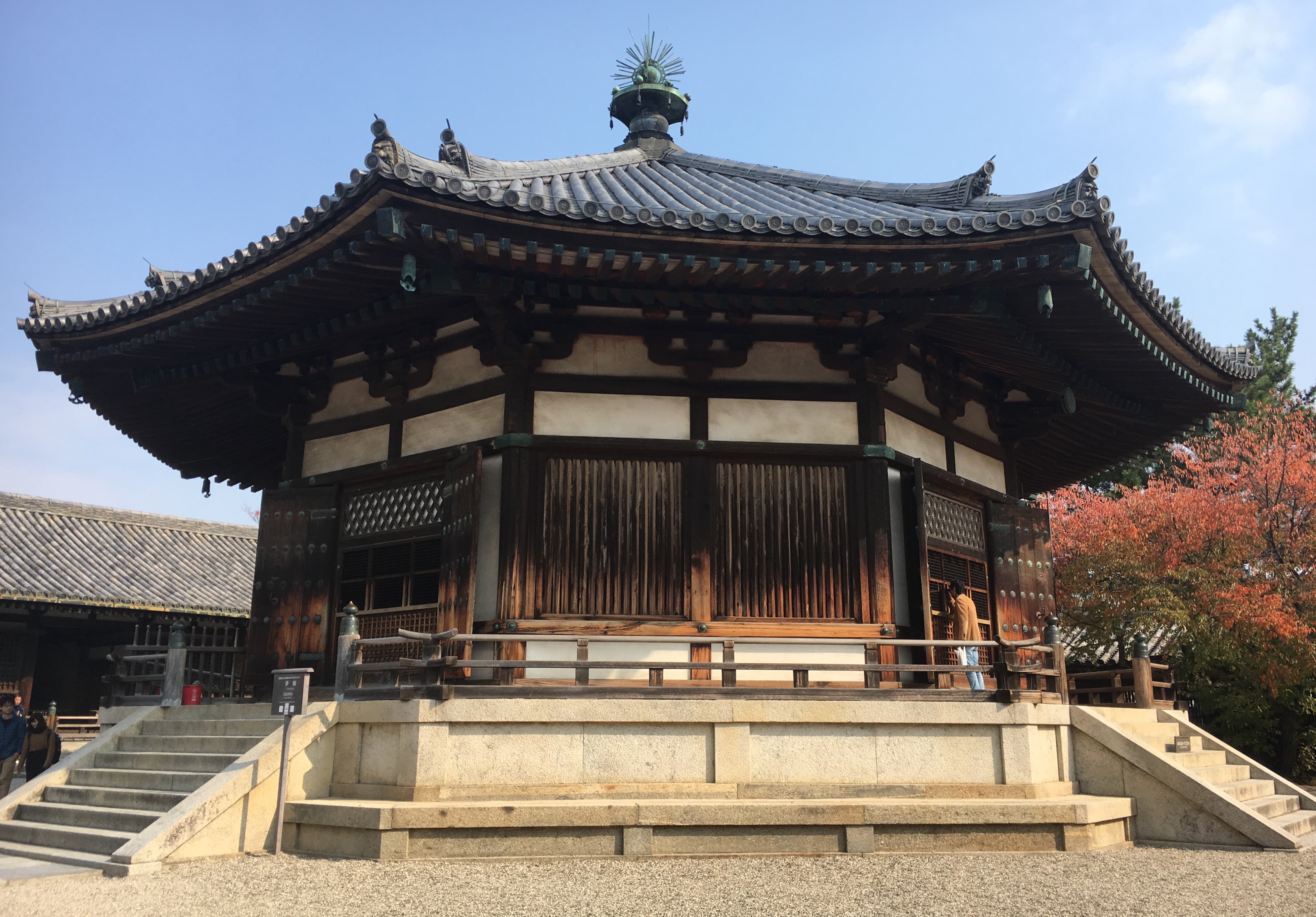 octagon shaped yumedono building in Horyu-ji temple surrounded by bright red leaves 