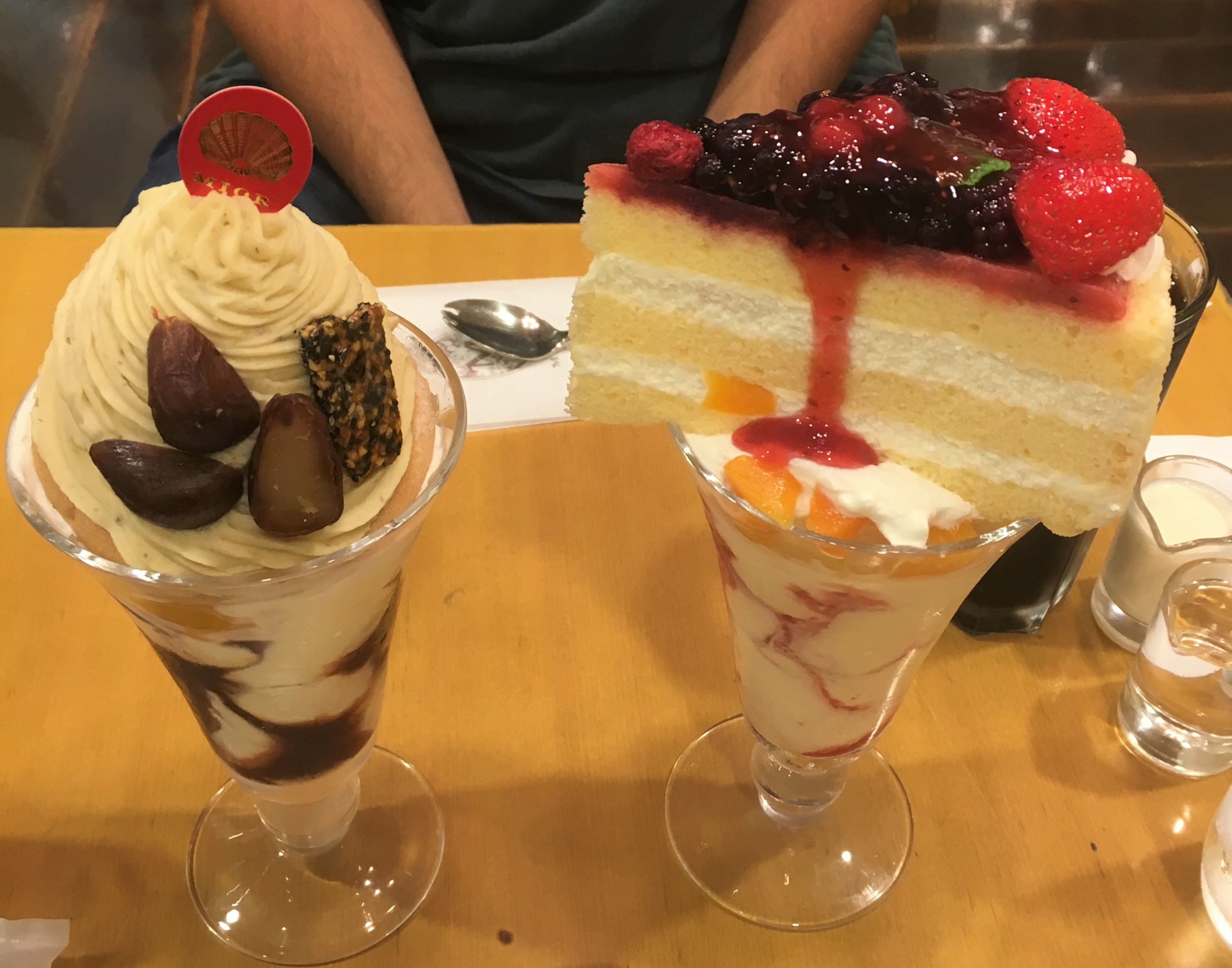large ice cream parfaits topped with while slices of different kinds of cake