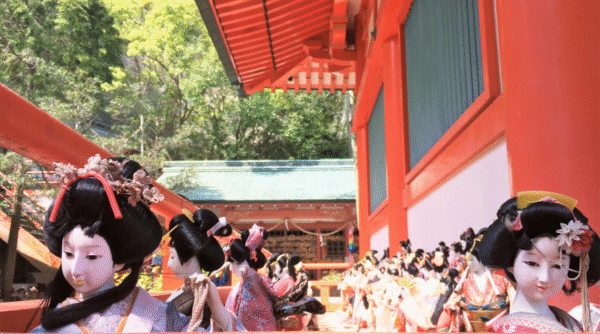 Japanese dolls standing outside of the hondo of Awashima Shrine