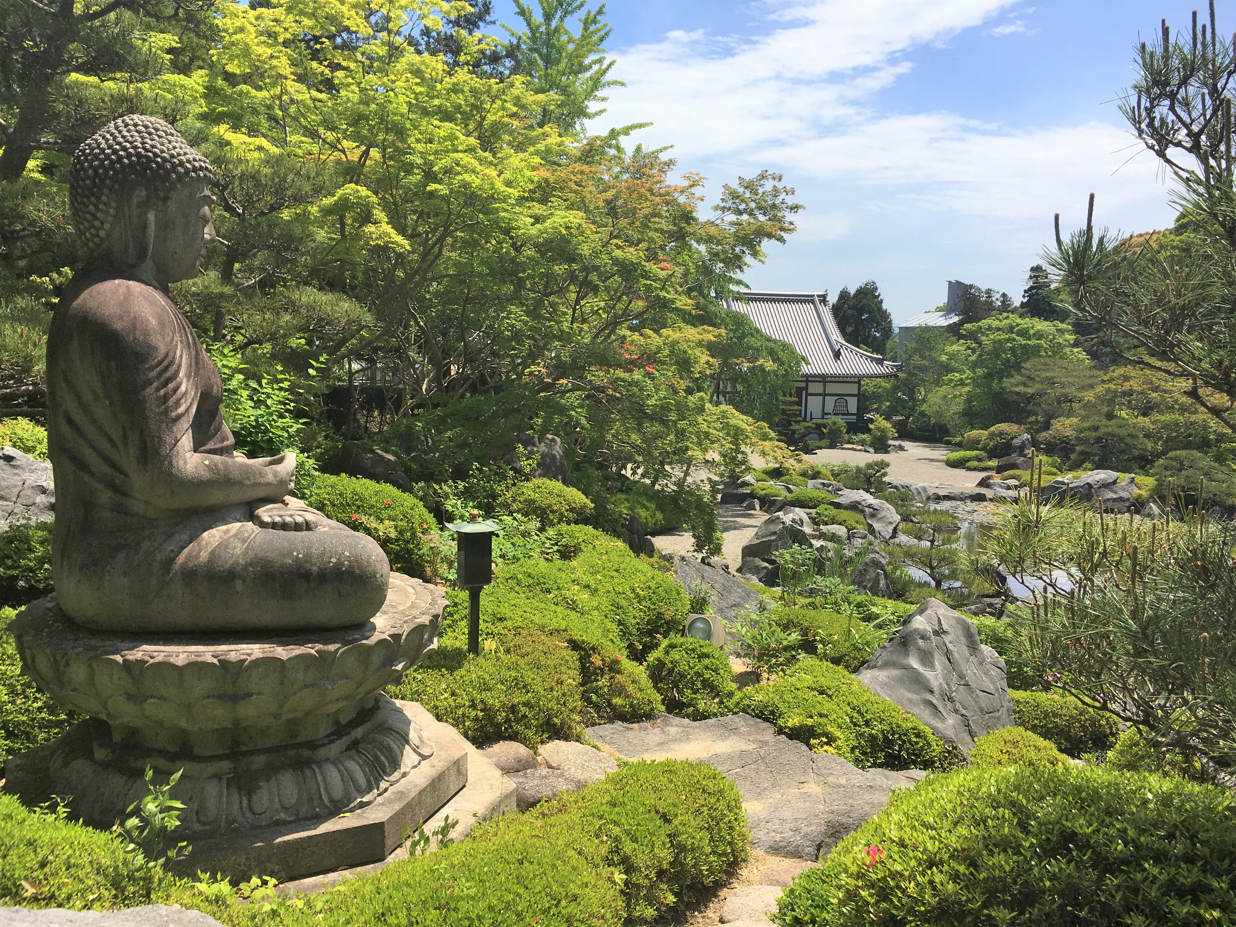 statue of buddha overlooking jodo garden in taima dera's okuno-in