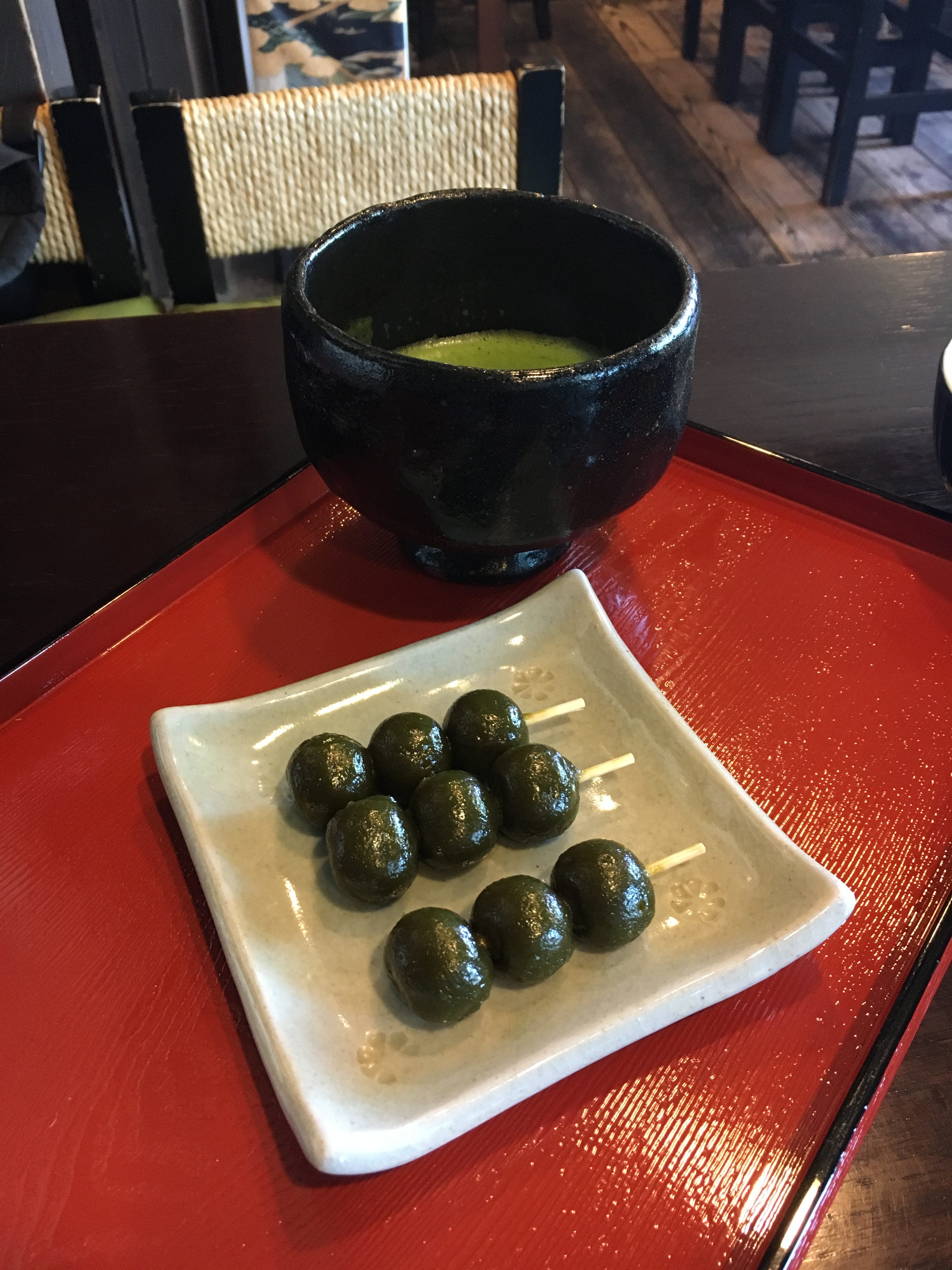 bowl of matcha tea and three sticks of green tea dango at tsuen