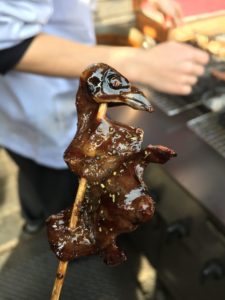 cooked roasted sparrow on a stick covered in sauce