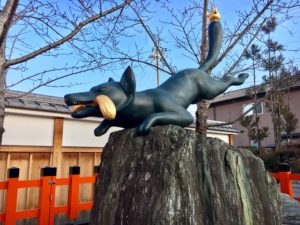 statue of a fox holding a bundle of rice