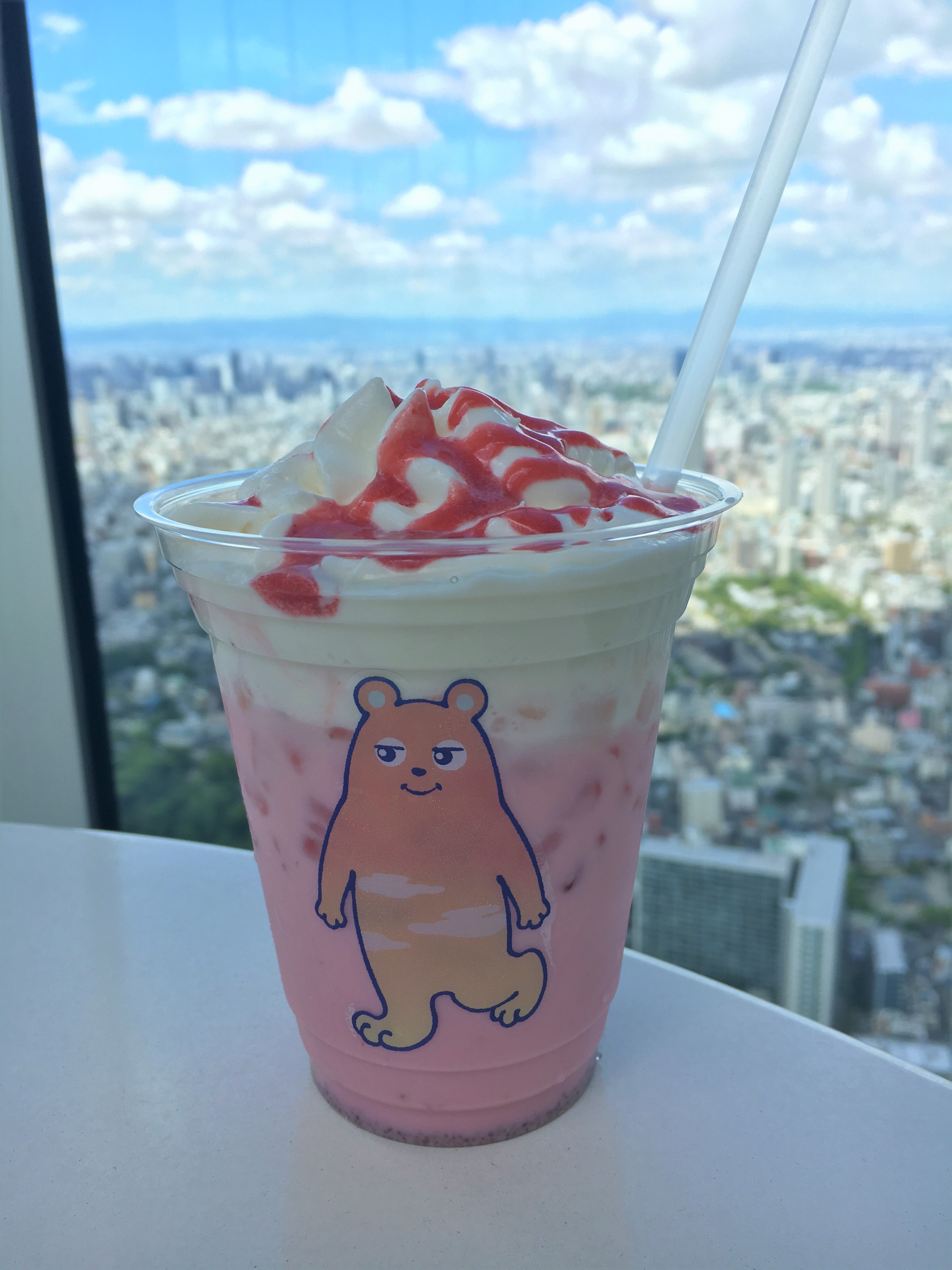 pink strawberry flavored latte with a picture of abeno bear on the cup