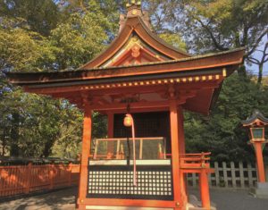 small vermillion biyako shrine with a large bell on a rope at fushimi inari taisha