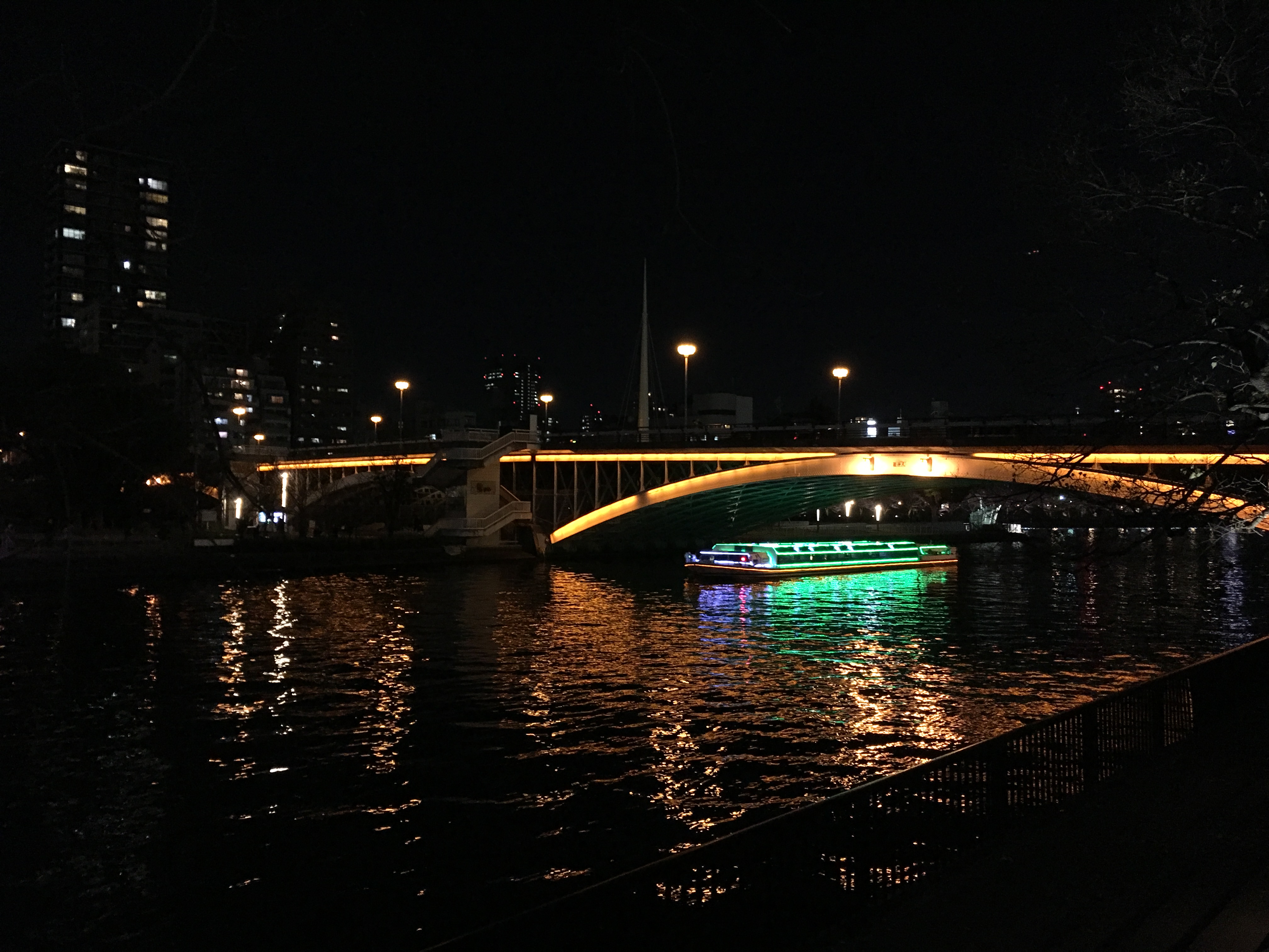Naniwabashi Bridge at night as a colorful illuminated aqua-liner sails under it