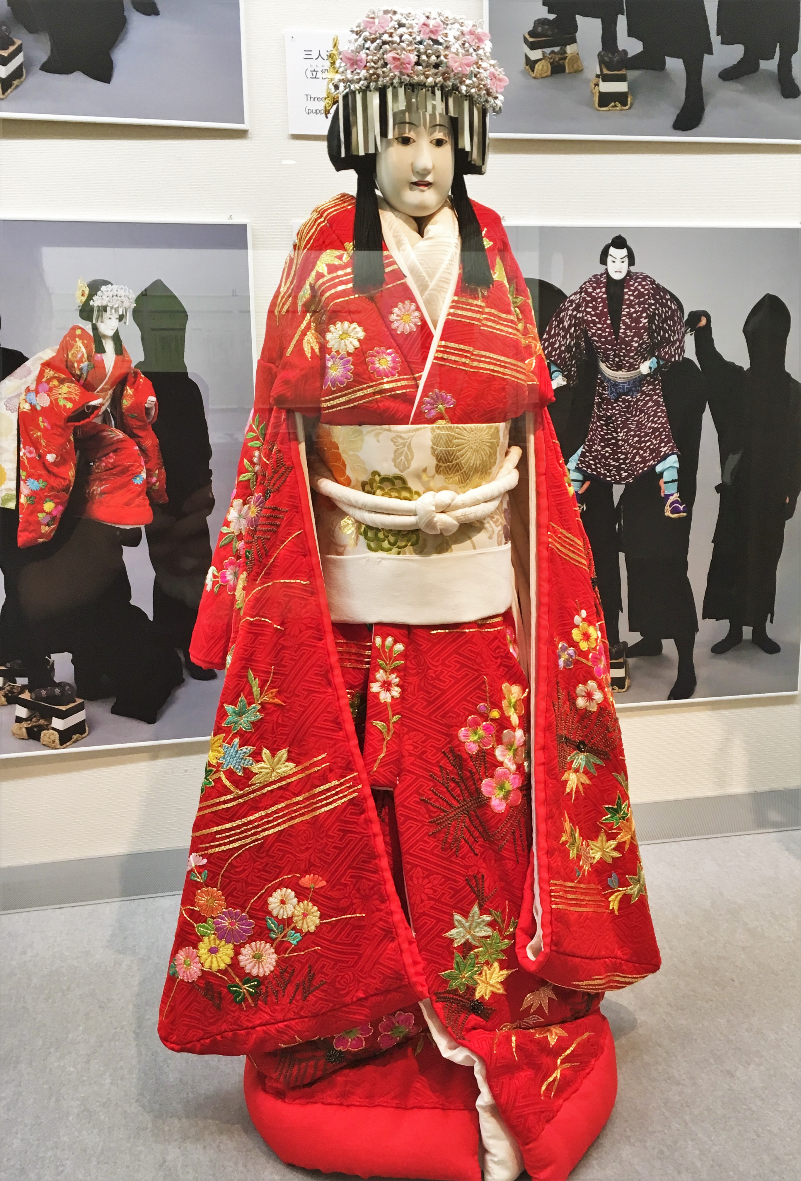 bunraku puppet dressed in a chrerry blossom and silver head dress and a red kimono
